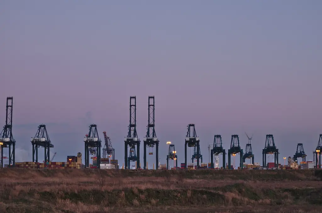 Row of container cranes silhouetted against the evening sky at a container terminal
