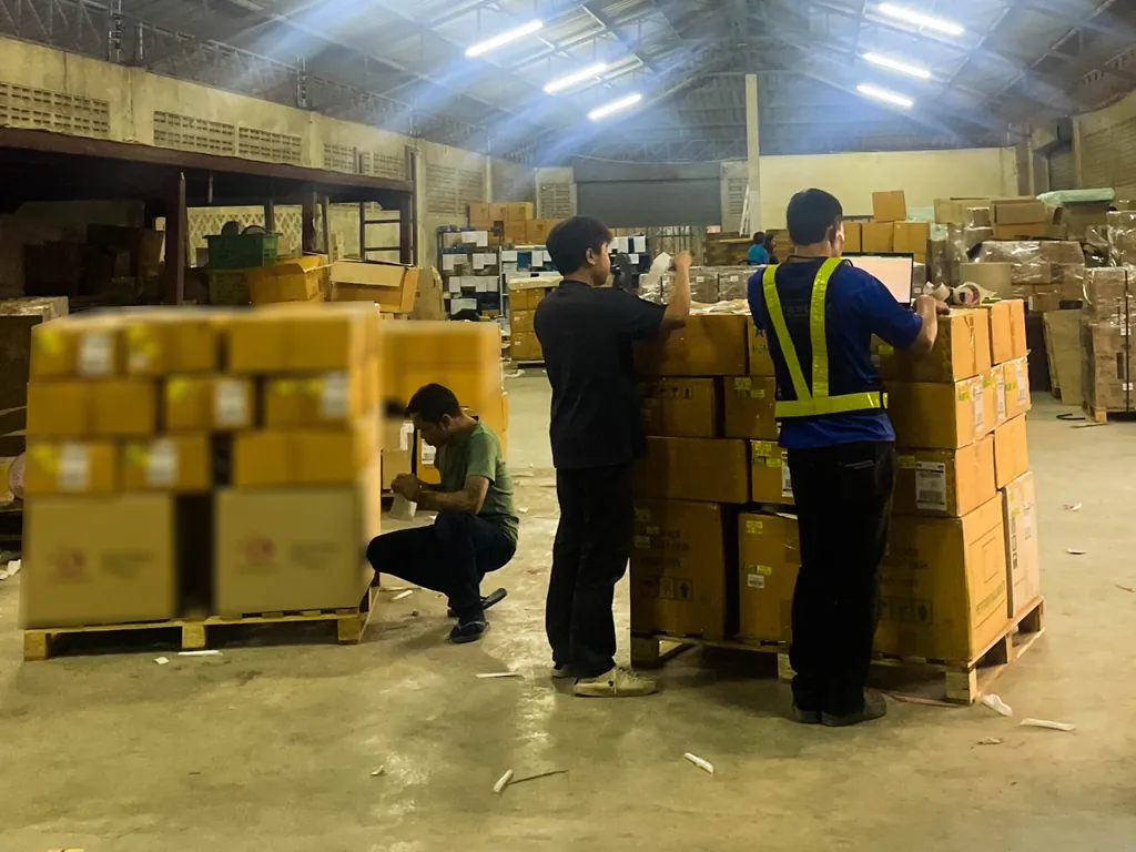 Warehouse staff checking and preparing palletised cartons for loading
