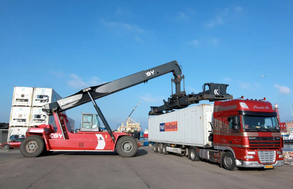 A reach stacker lifting a shipping container onto a truck trailer